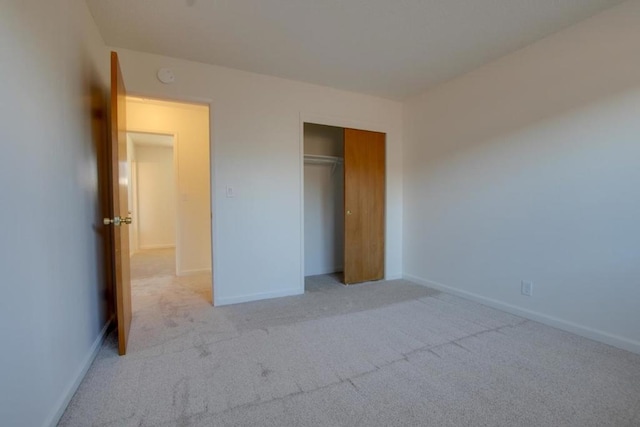 unfurnished bedroom with light carpet and a closet