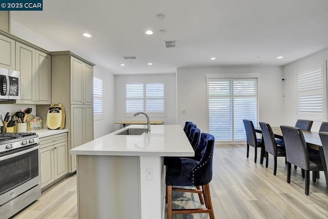 kitchen featuring a kitchen breakfast bar, appliances with stainless steel finishes, light hardwood / wood-style floors, and sink