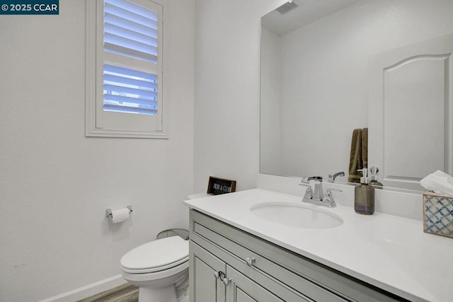 bathroom with toilet, hardwood / wood-style flooring, and vanity