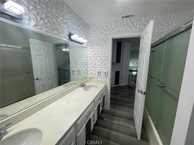 bathroom with hardwood / wood-style floors, vanity, and a shower with shower door