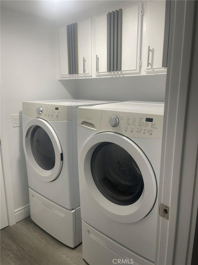 washroom with washer and clothes dryer, cabinets, and light wood-type flooring