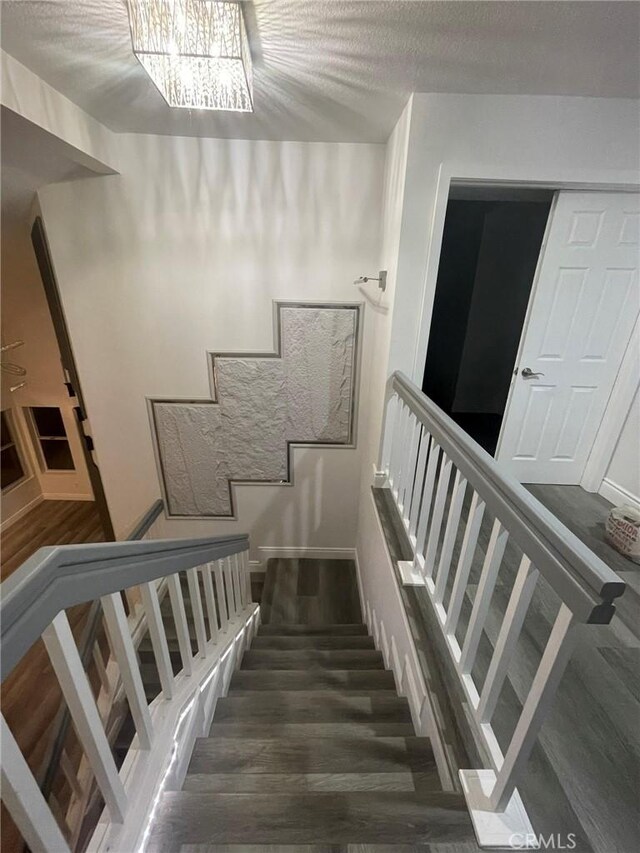 staircase with hardwood / wood-style floors and a notable chandelier