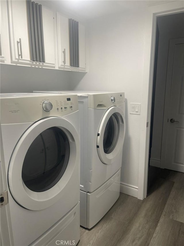 washroom with hardwood / wood-style floors, washer and dryer, and cabinets