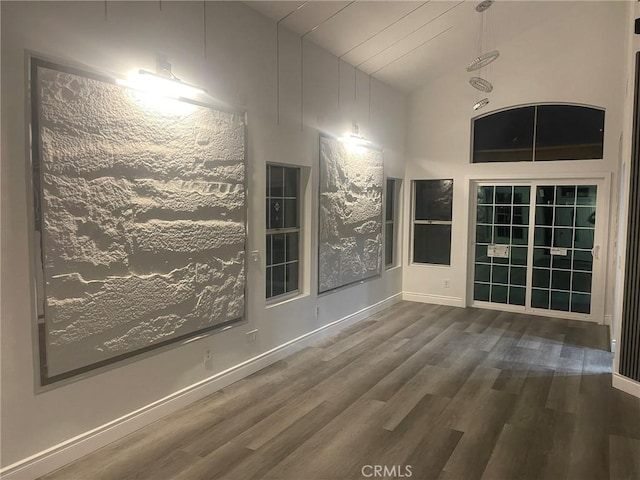 unfurnished room featuring dark wood-type flooring and high vaulted ceiling