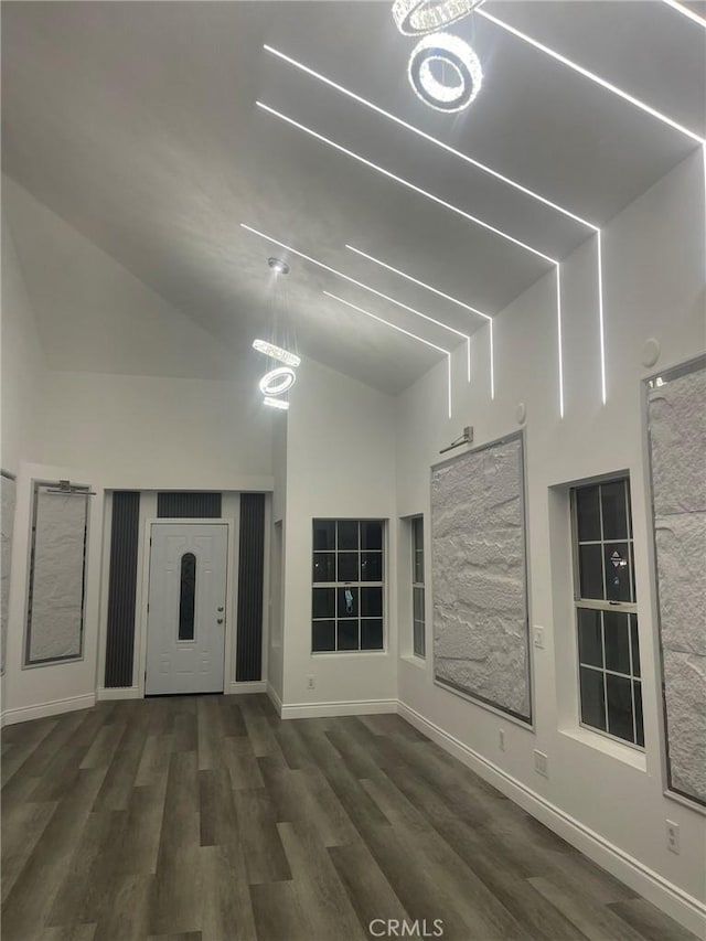 unfurnished living room with a notable chandelier, dark wood-type flooring, and high vaulted ceiling