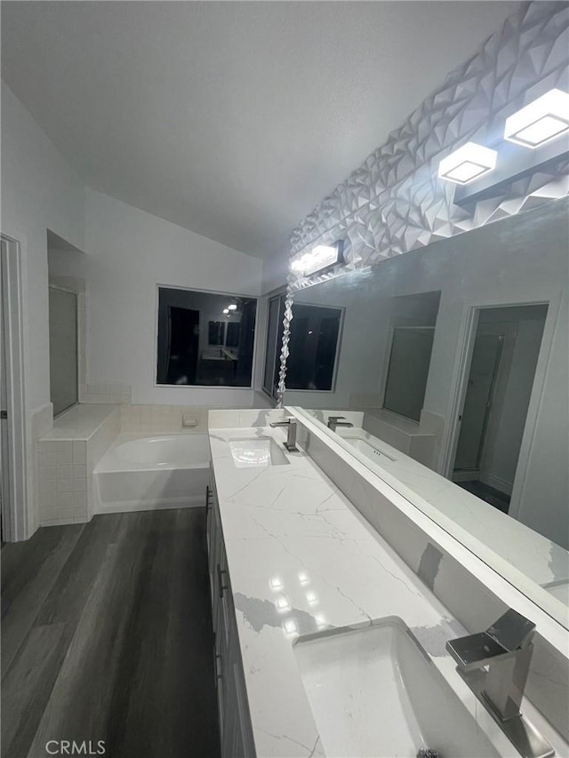 bathroom featuring a tub to relax in, hardwood / wood-style floors, vanity, and lofted ceiling