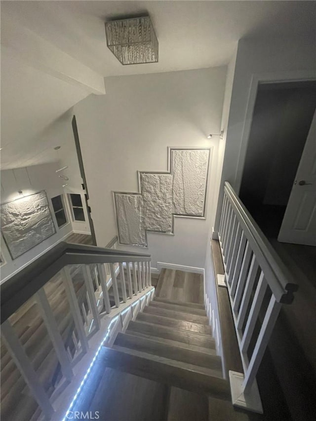 staircase featuring vaulted ceiling with beams and hardwood / wood-style floors