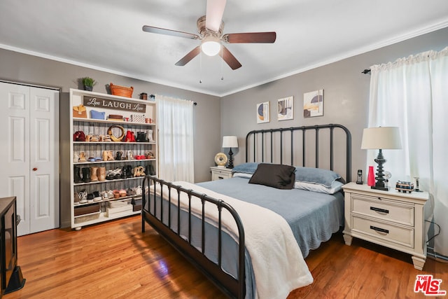 bedroom with hardwood / wood-style floors, ceiling fan, crown molding, and a closet