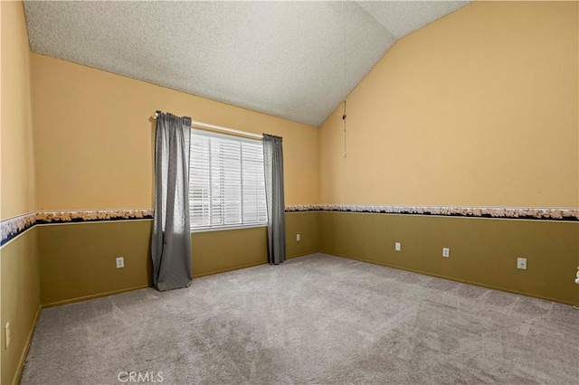 unfurnished room featuring a textured ceiling, light colored carpet, and lofted ceiling