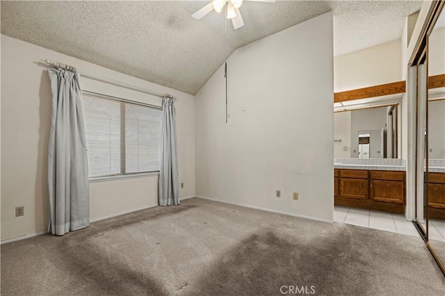 unfurnished bedroom with lofted ceiling, ensuite bathroom, ceiling fan, a textured ceiling, and light colored carpet