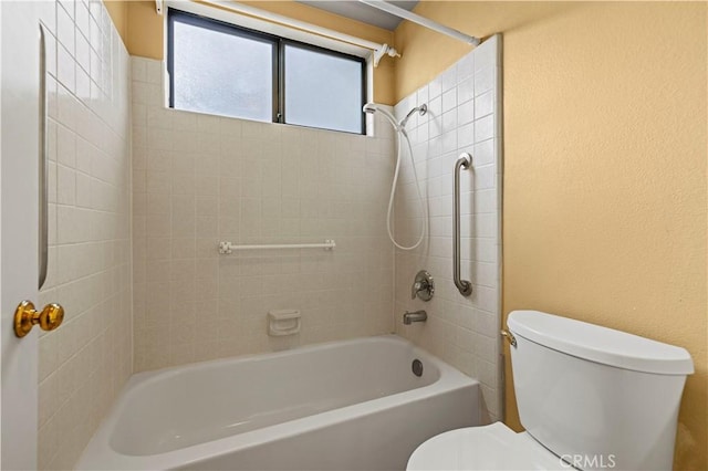 bathroom with toilet and tiled shower / bath