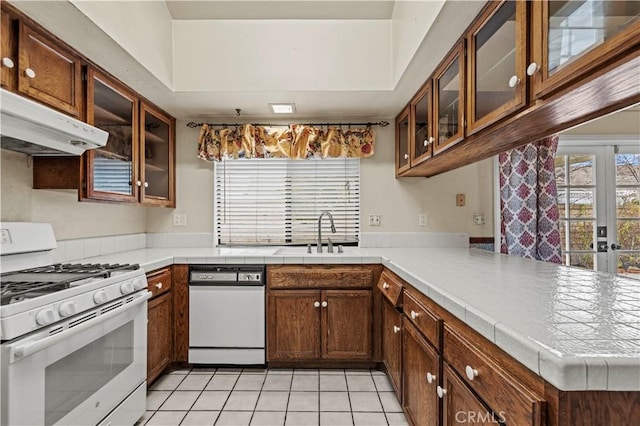 kitchen featuring kitchen peninsula, white appliances, sink, light tile patterned floors, and tile countertops