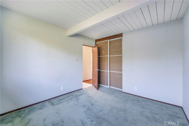 unfurnished bedroom with carpet and beam ceiling