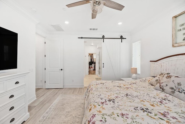 bedroom featuring ceiling fan, a barn door, ornamental molding, and light hardwood / wood-style flooring