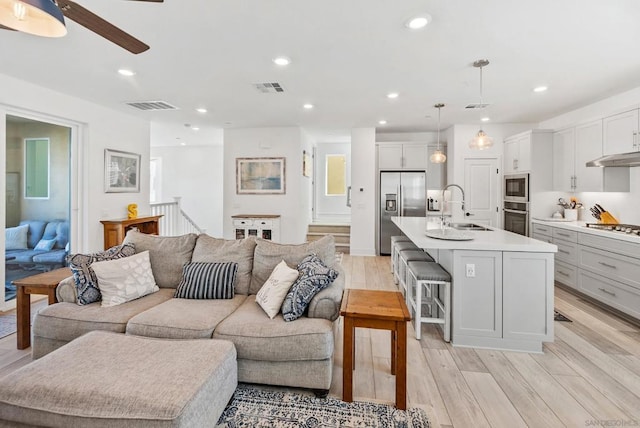 living room with ceiling fan, light hardwood / wood-style floors, and sink