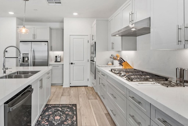 kitchen with sink, pendant lighting, light hardwood / wood-style floors, white cabinets, and appliances with stainless steel finishes