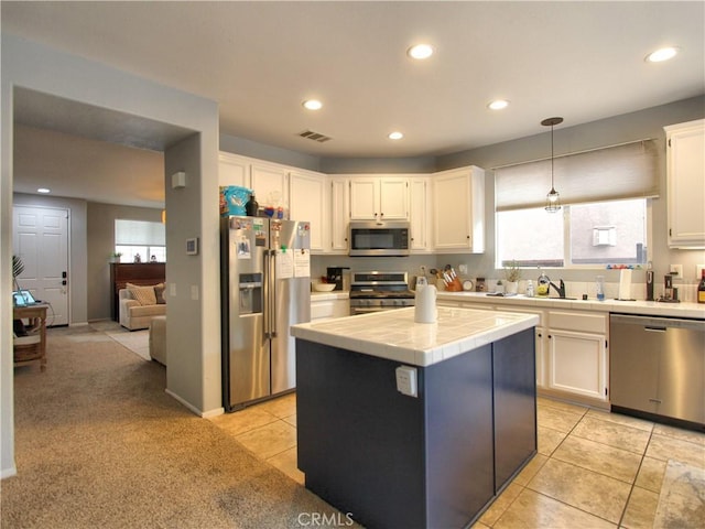 kitchen featuring tile counters, pendant lighting, light carpet, white cabinets, and appliances with stainless steel finishes