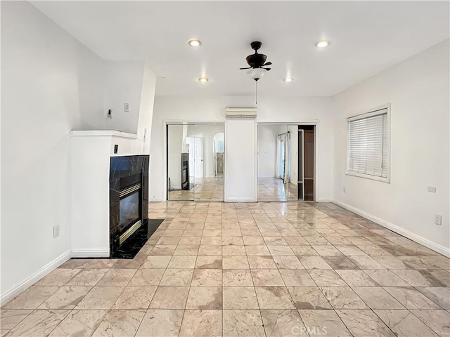 unfurnished living room featuring a high end fireplace, ceiling fan, and a wall unit AC