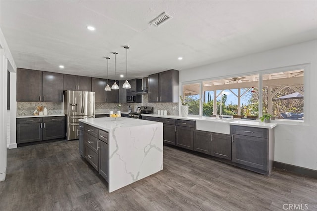 kitchen featuring stainless steel appliances, dark wood finished floors, visible vents, and a sink