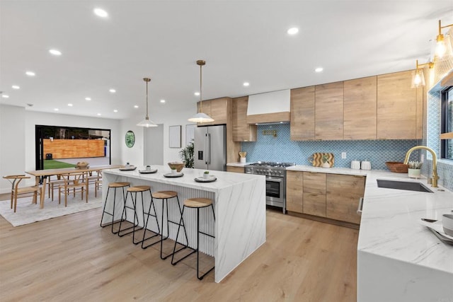 kitchen with premium range hood, appliances with stainless steel finishes, decorative light fixtures, a kitchen island, and sink