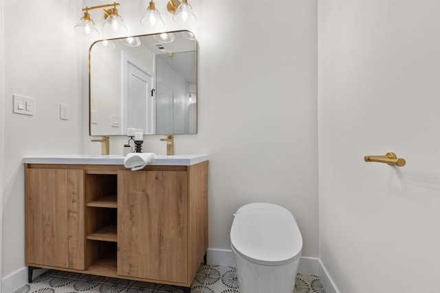 bathroom with toilet, vanity, and tile patterned flooring