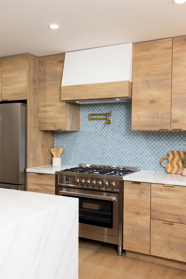 kitchen with light wood-type flooring, decorative backsplash, stainless steel appliances, and custom range hood