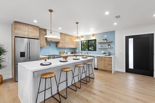 kitchen featuring pendant lighting, appliances with stainless steel finishes, a center island, backsplash, and a breakfast bar