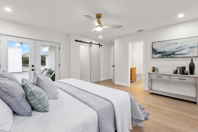 bedroom featuring ensuite bathroom, light hardwood / wood-style floors, a barn door, ceiling fan, and access to outside