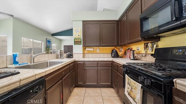 kitchen with sink, light tile patterned floors, dark brown cabinets, black appliances, and tile countertops