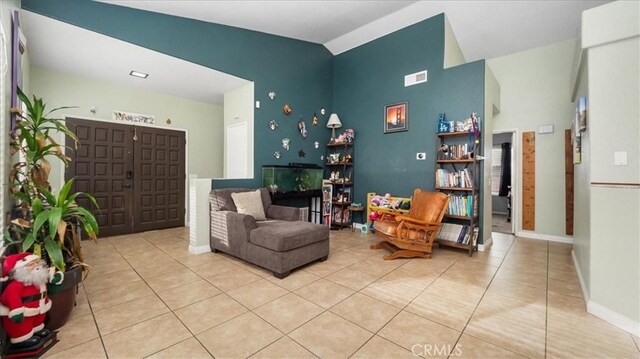 living area with lofted ceiling and light tile patterned floors