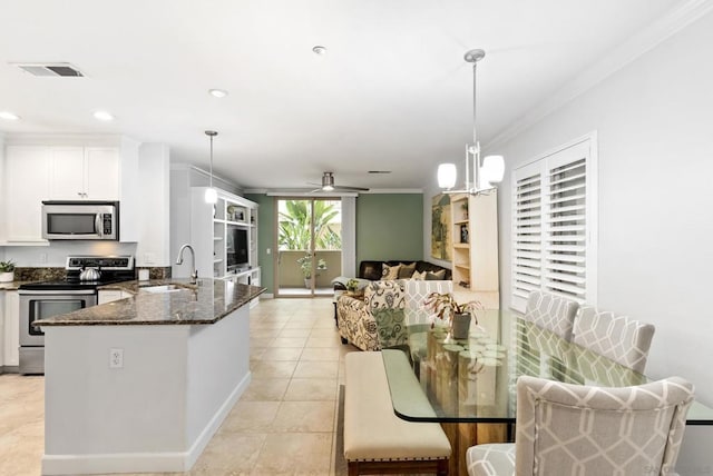 kitchen featuring white cabinetry, sink, dark stone countertops, decorative light fixtures, and appliances with stainless steel finishes