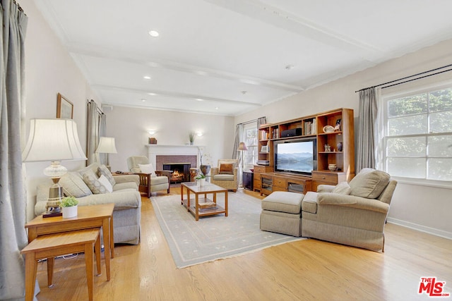 living room with a brick fireplace, beamed ceiling, and light wood-type flooring