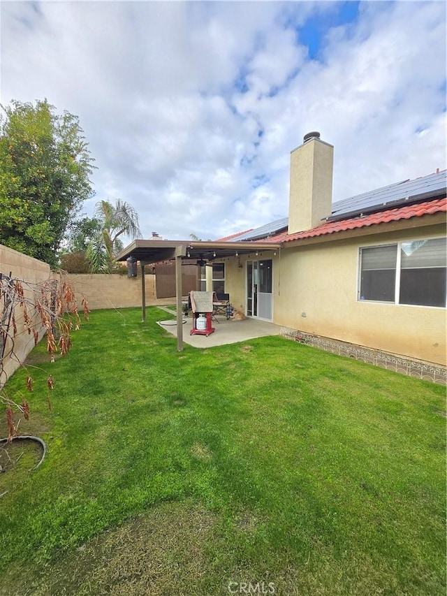 back of house with a lawn, a patio, and solar panels