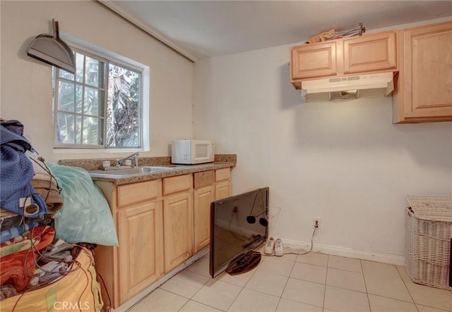 kitchen with light brown cabinetry, sink, and light tile patterned flooring