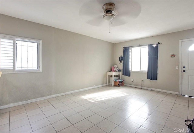 empty room with ceiling fan and light tile patterned floors