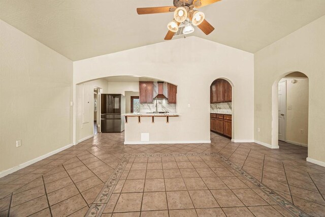 unfurnished living room with ceiling fan, light tile patterned flooring, and high vaulted ceiling