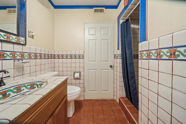 bathroom with a shower with curtain, vanity, tile walls, tile patterned flooring, and toilet