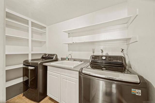 laundry area with sink, cabinets, light wood-type flooring, and independent washer and dryer