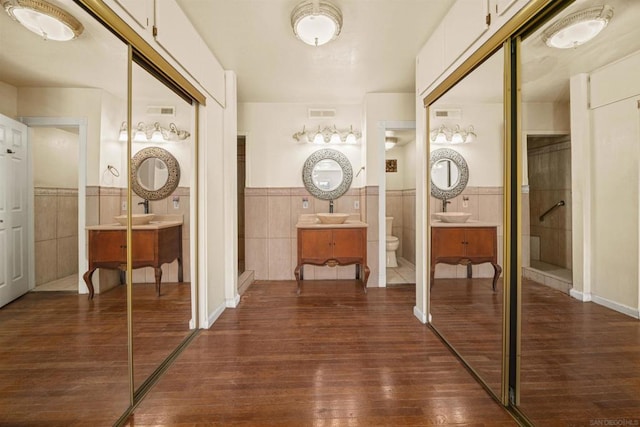 bathroom with vanity, wood-type flooring, tile walls, and toilet