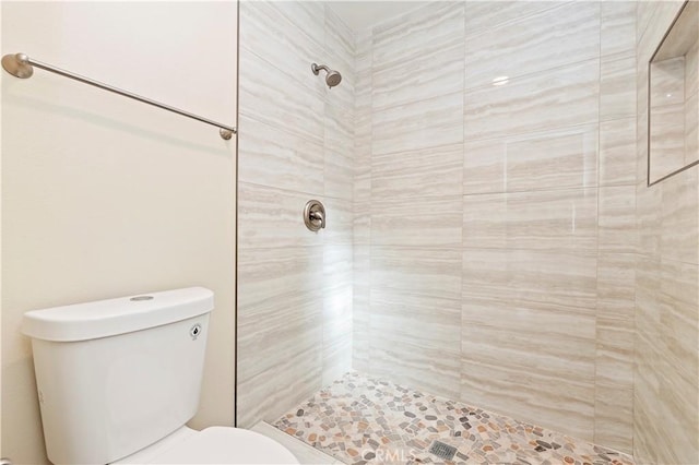 bathroom with toilet and a tile shower