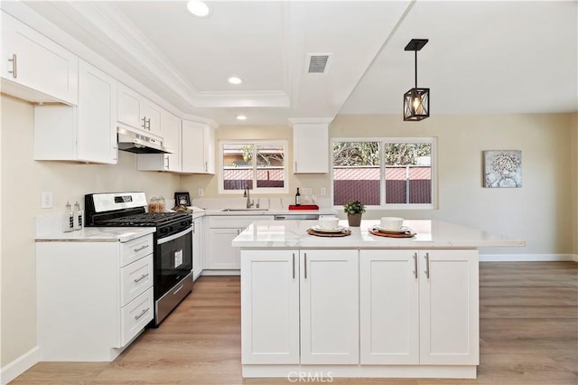 kitchen featuring white cabinetry, light wood-type flooring, stainless steel range with gas cooktop, and hanging light fixtures