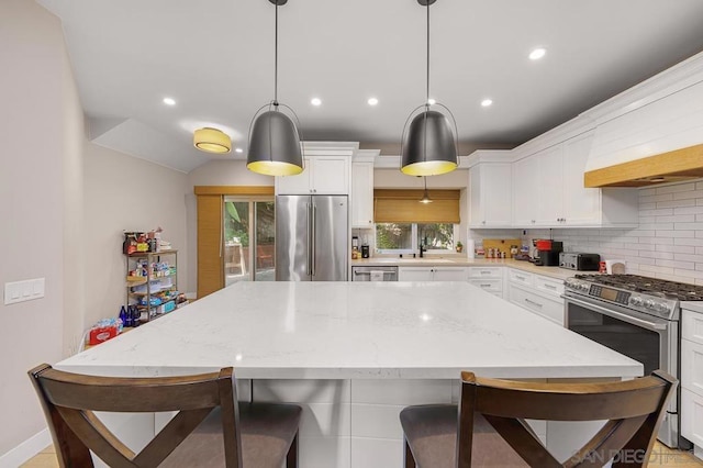 kitchen with pendant lighting, white cabinets, a healthy amount of sunlight, and appliances with stainless steel finishes