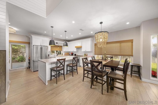 dining room with plenty of natural light, light hardwood / wood-style floors, and an inviting chandelier