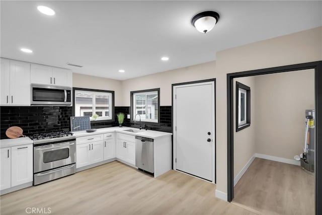 kitchen featuring appliances with stainless steel finishes, sink, white cabinetry, and light hardwood / wood-style floors