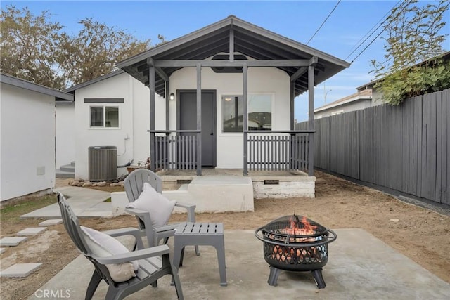 rear view of property featuring a fire pit and central air condition unit