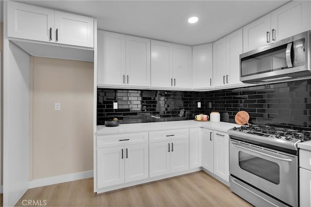 kitchen featuring white cabinets, decorative backsplash, stainless steel appliances, and light hardwood / wood-style floors