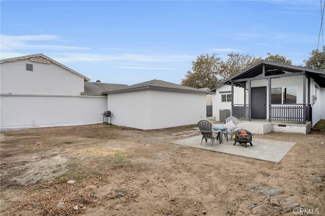 rear view of house with a patio area, cooling unit, and a fire pit