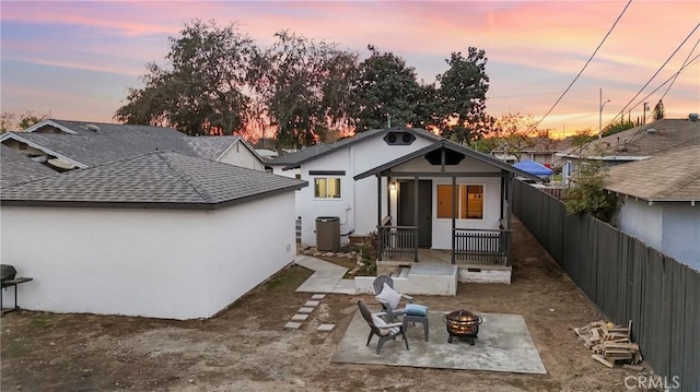 back house at dusk featuring central AC unit, a patio area, and an outdoor fire pit