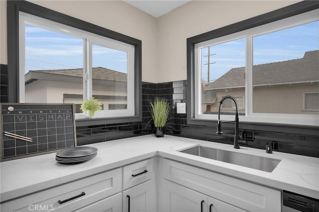 kitchen with stainless steel dishwasher, sink, white cabinets, and plenty of natural light