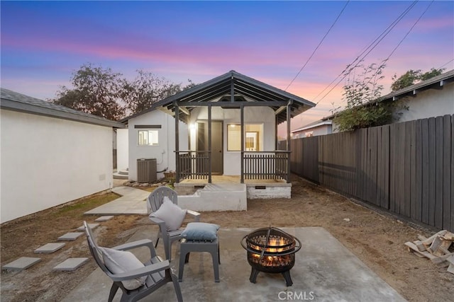 back house at dusk featuring a patio area, an outdoor fire pit, and central air condition unit